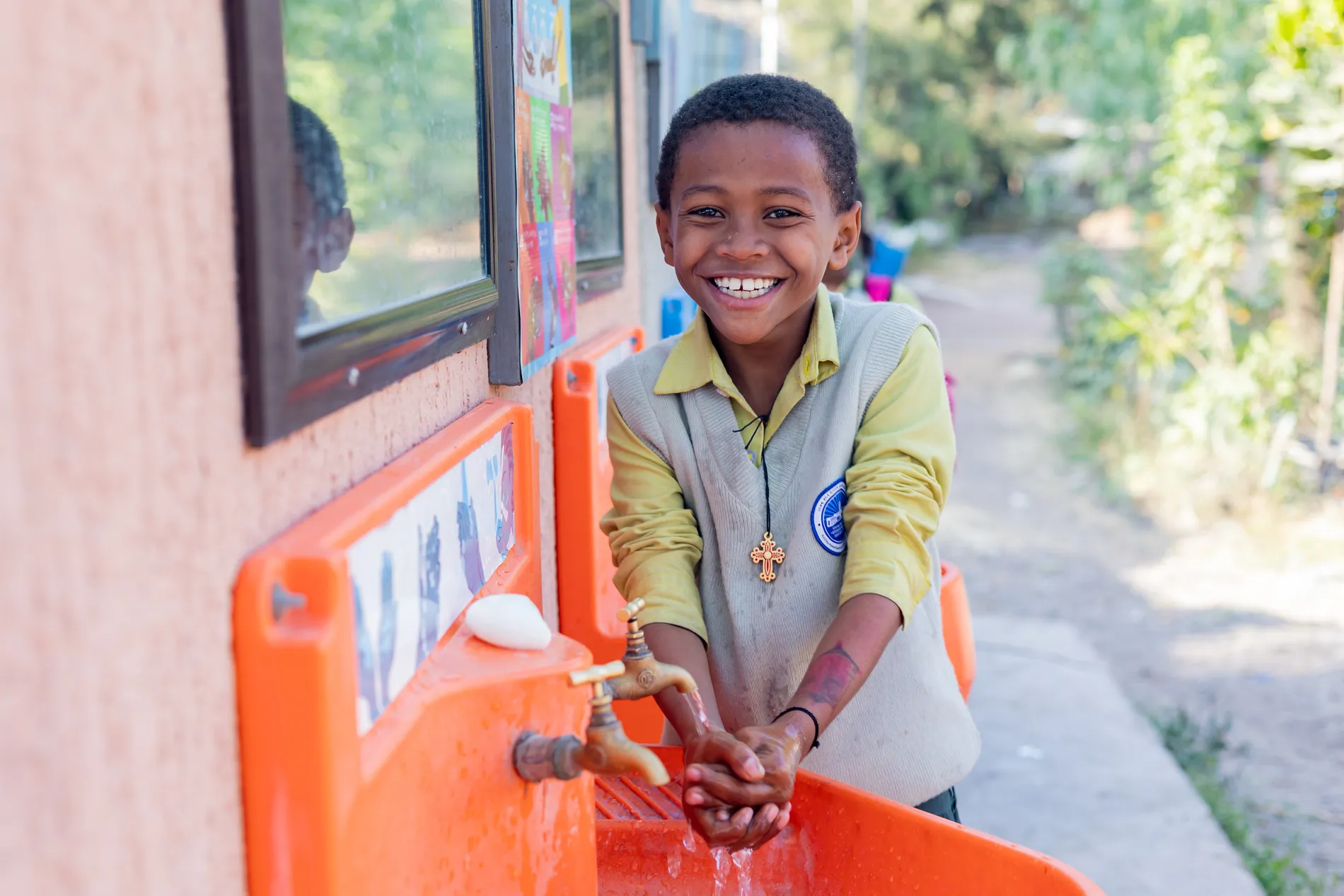 Boy joyfully washing hands at a Splash water station