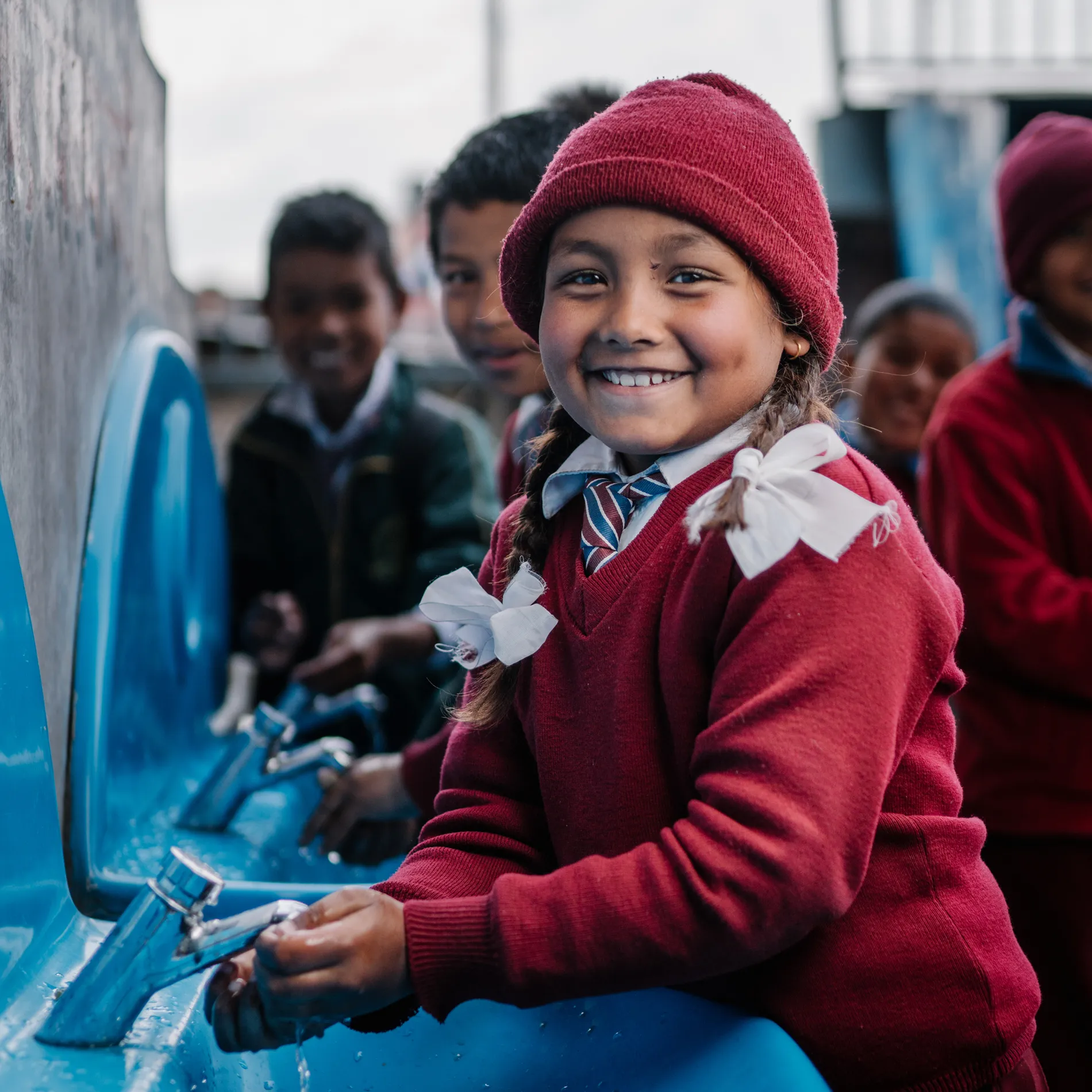 Girl washing hands at school tap
