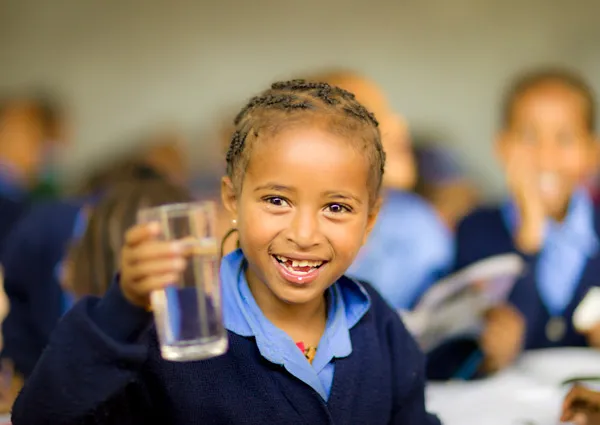 Girl smiling holding up a glass of clean water